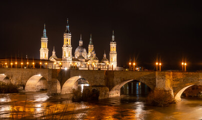 Fototapeta premium Long exposure at night on the Puente de Piedra next to the Basilica of Nuestra Señora del Pilar on the Ebro river in the city of Zaragoza, Aragon. Spain