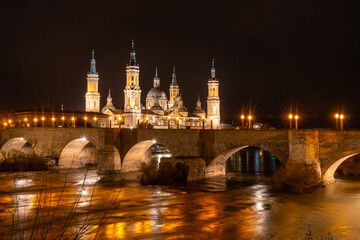Long exposure at night on the Puente de Piedra next to the Basilica of Nuestra Señora del Pilar on the Ebro river in the city of Zaragoza, Aragon. Spain