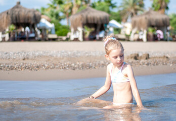 Fototapeta na wymiar Little girl playing on the beach by the sea