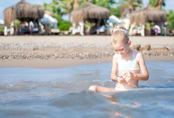 Little girl playing on the beach by the sea