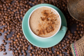 aromatic coffee in a cup of cappuccino with cinnamon and coffee beans. Top view of a hot drink