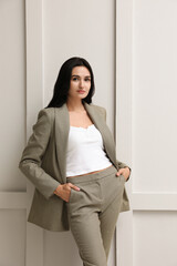 Beautiful woman in formal suit near light grey wall. Business attire