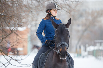 Obraz premium Portrait of teenage girl riding raven horse in winter.