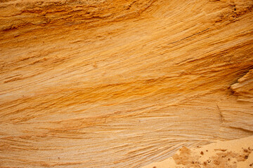 Obraz premium Textural sand, with relief surface, multi-colored layers and different in size of granules, in outdoor sand career, after mining ore and sand for construction.