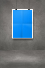Blue folded poster hanging on a dark concrete wall with clips