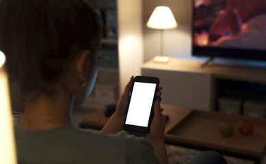 Teenager sitting on the couch and using her smartphone