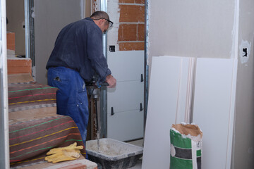 Senior constructor worker preparing tile adhesive mortar with a hand mixer.
