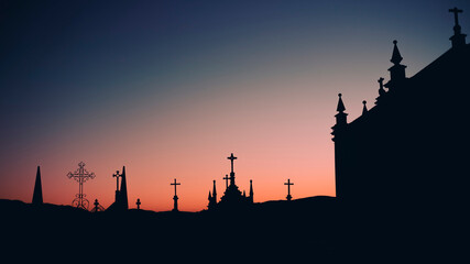 Silhouettes of crosses in a twilight cemetery.