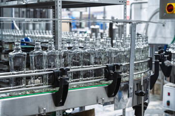 Conveyor belt transports empty glass bottles in workshop
