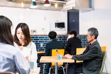 明るい雰囲気の社員食堂でランチを取るオフィスワーカー