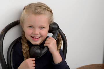Girl sitting on chair and talking by old phone