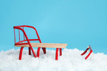 Sleigh and artificial snow on light blue background. Winter outdoor activity