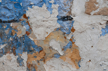 Multi-colored layers of peeling paint on stonework and walls of old buildings.