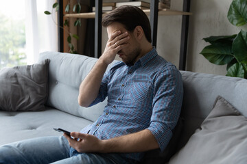 Confused 35s man holds smartphone have problem with gadget, feels frustrated due cellphone...