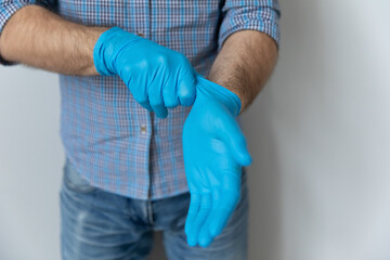 Close up midsection view man wear medical protective rubber gloves, on gray studio background. Preventive measures due COVID-19 pandemic outbreak. Self-care, personal safety, stop corona virus concept