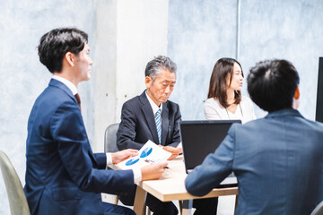 商品企画のプレゼンテーションを聞くビジネスパーソン