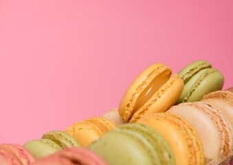 A pile of delicious Macaroons, French treats made of almonds with lime, pistachio and vanilla flavors , on a pink background 