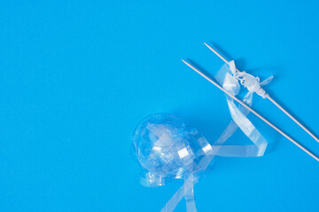 recycled plastic yarn concept, knitting needles, chopped plastic balls on bright blue background