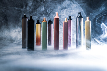 multicolored electronic cigarettes vape on dark background with smoke
