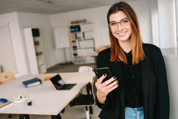 Happy friendly modern young businesswoman smiling at camera