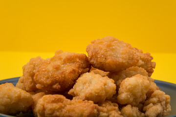 A plate of fried chicken with yellow background