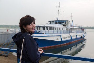 A brunette in a blue jacket awaits the arrival of the ship.