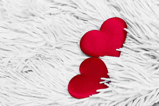two red scarlet plush hearts in the pile of a white carpet will be an excellent background for the decoration of a valentine's backdrop or a wedding invitation