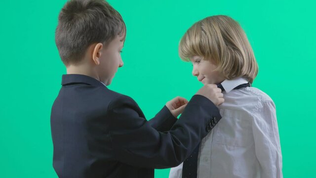 Bigger child arrange youngest brother tie, learning in family, green screen background, different generation, strong bond