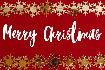 Fototapeta na wymiar Merry Christmas text on golden snowflakes christmas garland border on red background. Season's greetings card. Handwritten sign. Happy Holidays!