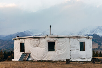 Round yurt in the autumn steppe against the background of snow-capped mountains