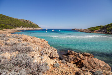 Fototapeta na wymiar Turquoise water, rocky coast line and boats at beautiful bay Cala Moltó at Mallorca island, Mediterranean Sea, Spain