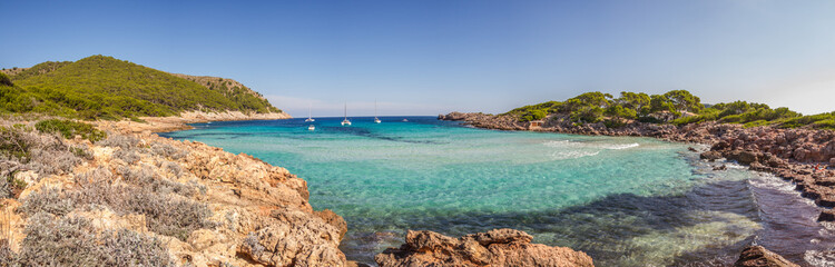 Fototapeta na wymiar Turquoise water, rocky coast line and boats at beautiful small bay Cala Moltó at Mallorca island, Mediterranean Sea, Spain (Panorama)