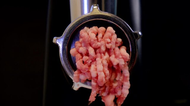 Minced meat cooking process. Household meat grinder front view. 4K footage with dark background