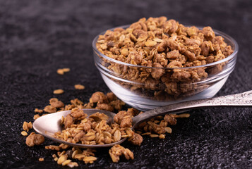 Healthy homemade muesli in a glass bowl on a black background.