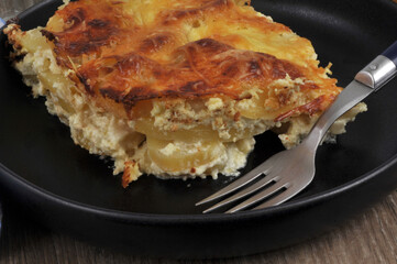 Portion de gratin de pommes de terre servie dans une assiette avec une fourchette en gros plan
