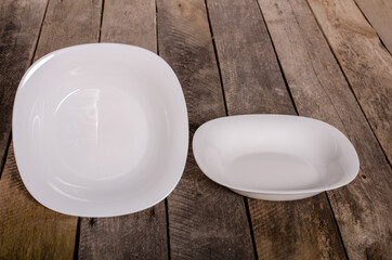 Top view of blank white dish and white tablecloth on a wood background with copy space
