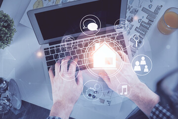 Double exposure of man's hands typing over computer keyboard and buildings drawing. Top view. smart city concept.