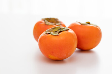 三つのおいしそうな柿と真っ白な背景