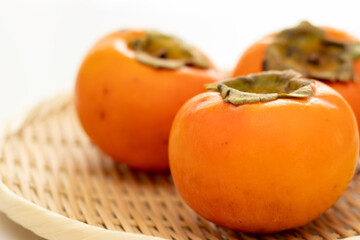 竹のザルにのせられたおいしそうな柿