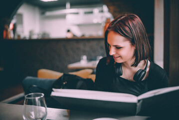 young teenager girl student drawing with pencil in paper album sitting in cafe