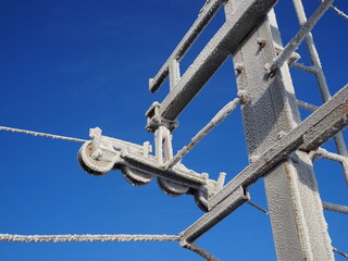 Top ski lift wheel covered with icing and blue sky