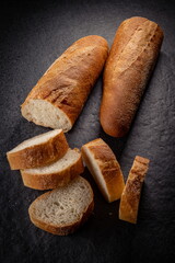 Fresh baked Baguette Loaf on Stone Plate Slices Two Halves Perspective View