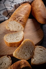 Fresh baked Baguette Loaf on wooden Cutting board With a Kitchen Towel Sliced Perspective View