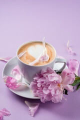 Fototapeta na wymiar Female hands holding a cup of coffee. Blouse with romantic pink background and rose petals.
