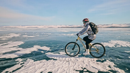 Fototapeta premium Woman is riding bicycle on the ice. Tires on bike are covered wi
