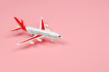 White toy plane on a pink background. Travel concept