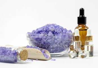 Lavender sea salt in a bowl and essential oils on a white background, selective focus. Body care products