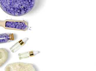 Lavender sea salt, oils in transparent bottles and loofah washcloth on a white background with...