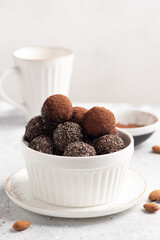 Raw energy balls made of dates, nuts, chia seeds in white bowl. Vegan chocolate truffles. vertical image. copy space
