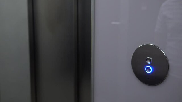 A man pushes an elevator button in a hallway and waits - closeup